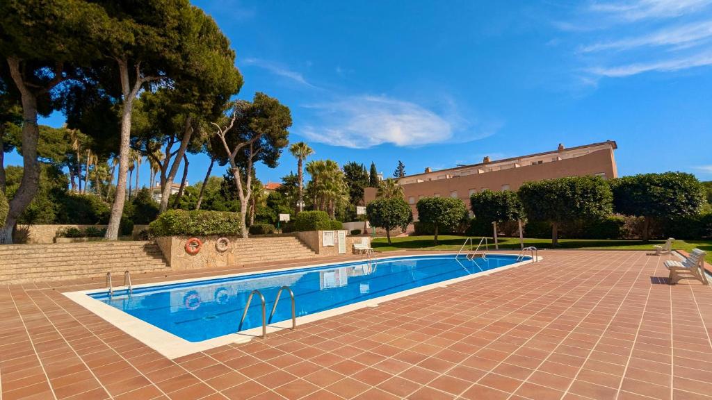 a swimming pool in a courtyard with trees and a building at EVH114 Casa con piscina comunitaria in Altafulla