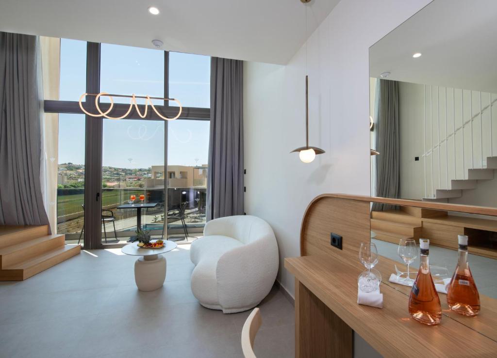 a living room with a white chair and a large window at Ventale Island Breeze Resort in Georgioupolis