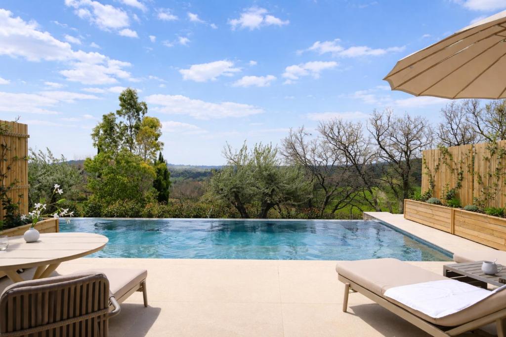 an infinity pool with a table and chairs and an umbrella at La Bastide des Rameaux - Boutique Hôtel & Spa in Callas