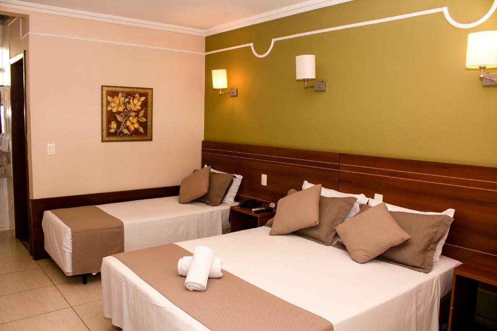 a hotel room with two beds and a table at Hotel Dom Otto in Vespasiano