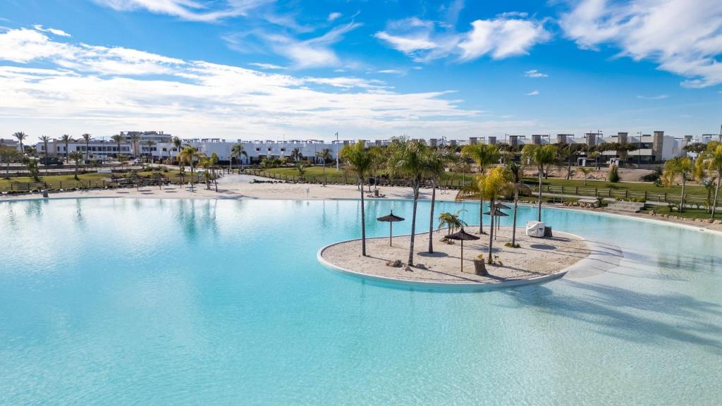 a large swimming pool with palm trees and a beach at Nieuw Casa Santa Rosalia uitzicht op zwembad in Torre-Pacheco