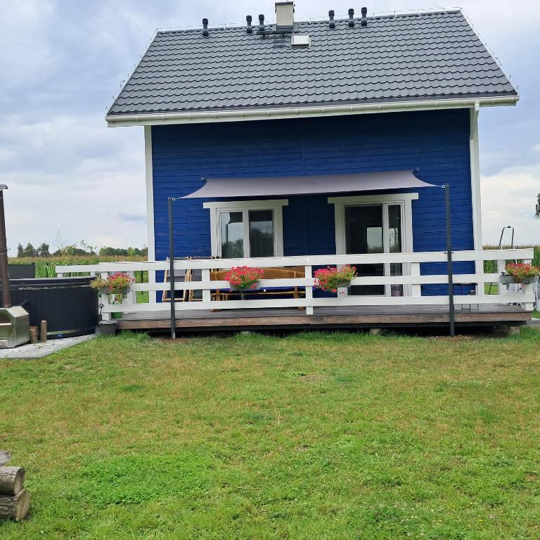 a blue house with flowers on the front porch at Sarenkowo dom z balia ogrodowa in Pokrzywnica