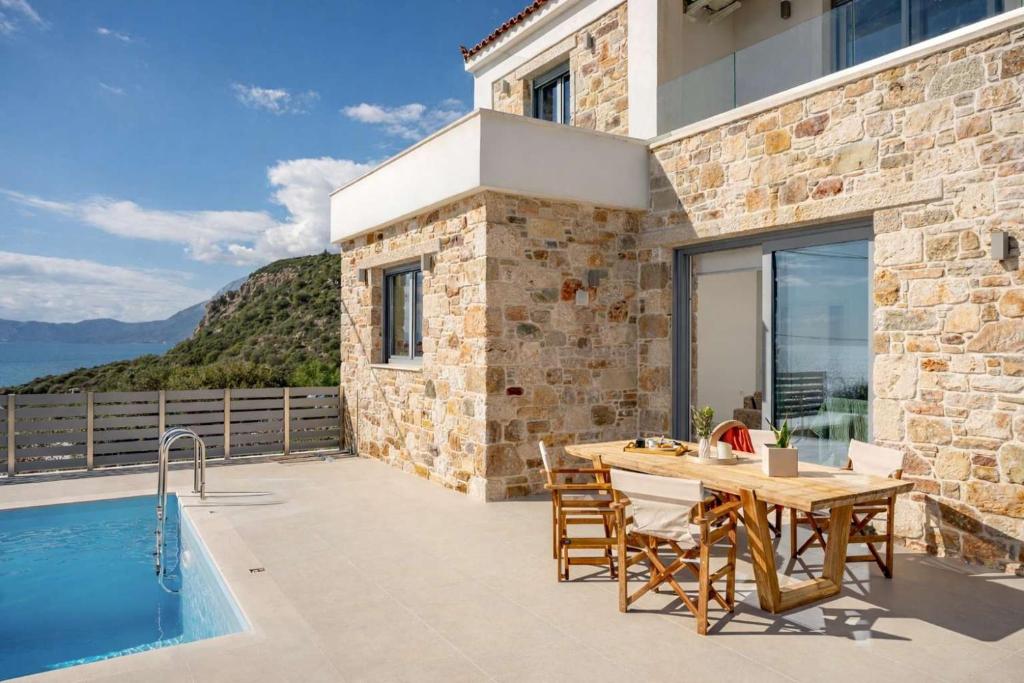a villa with a table and a swimming pool at Villa Alexia - Private Pool & Panoramic Sea Views in Órmos Koumaíïkon