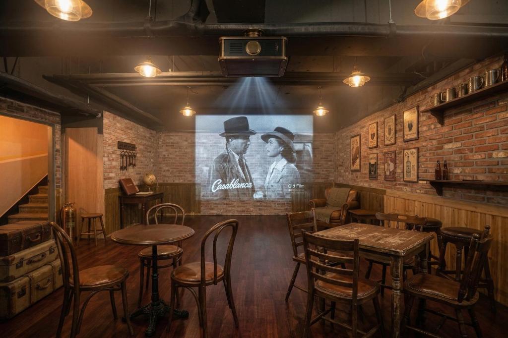 a restaurant with two tables and a movie projected on the wall at Midpoint Guesthouse in Busan