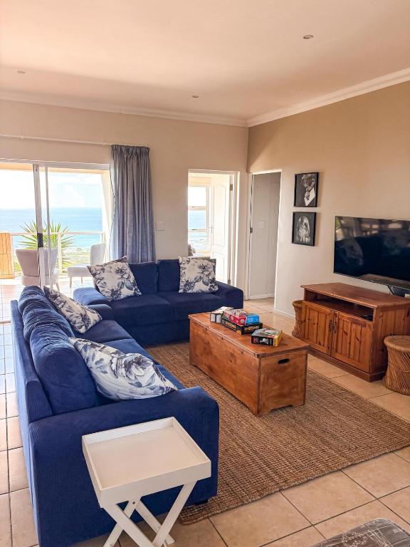 a living room with a blue couch and a table at On The Hill in Stompneusbaai