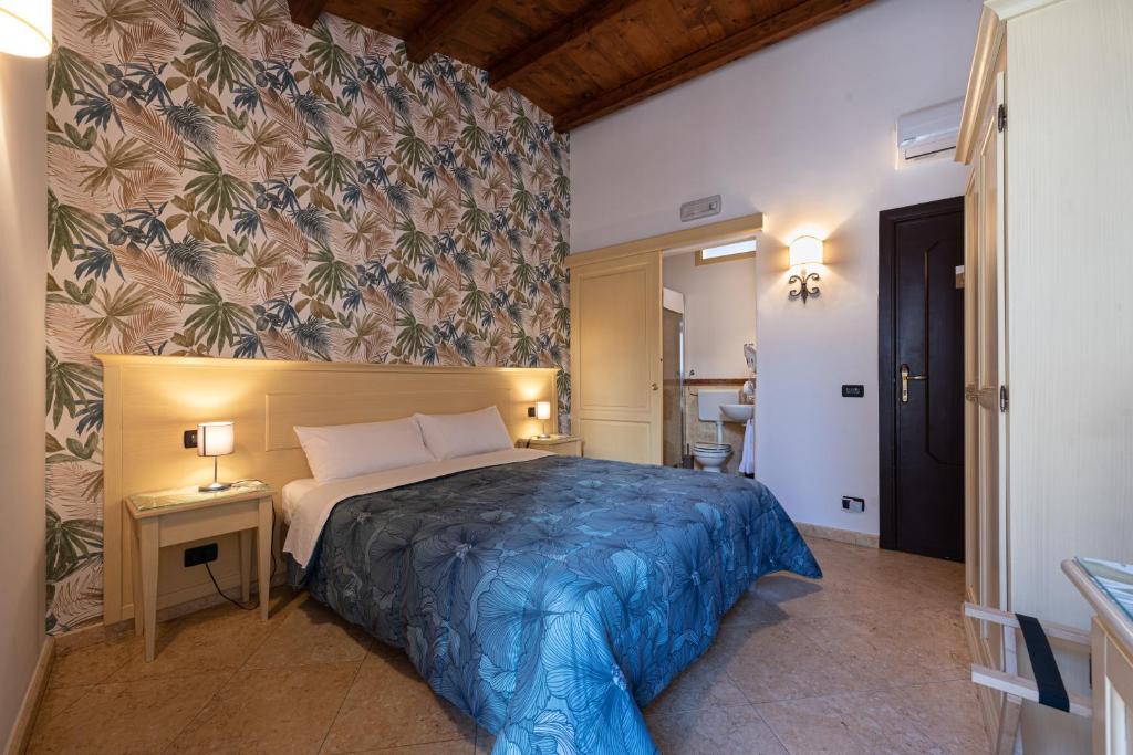 a bedroom with a bed with a blue comforter at Duomo Apartments Affittacamere in Cefalù