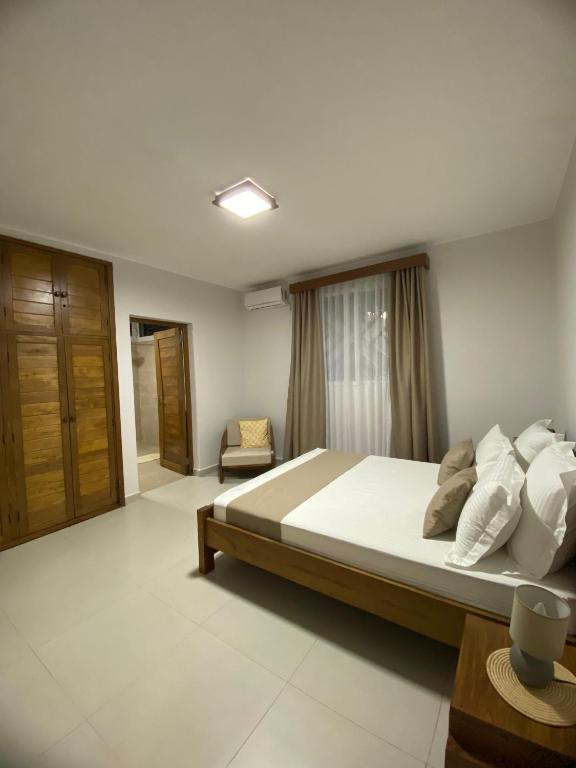 a bedroom with a large bed and a chair at Hasoa Villa in Morondava