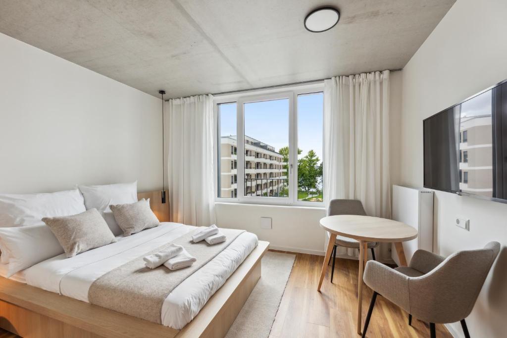 a bedroom with a bed and a table and a window at Habyt Berlin Waterfront in Berlin