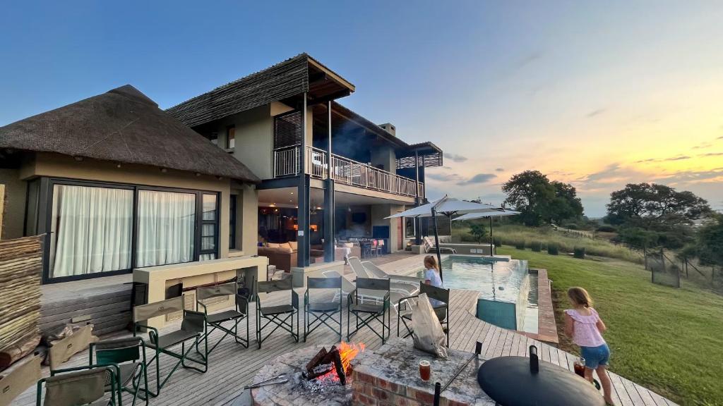 two people standing on a deck in front of a house at Jacana River Lodge Mjejane Game Reserve in Hectorspruit