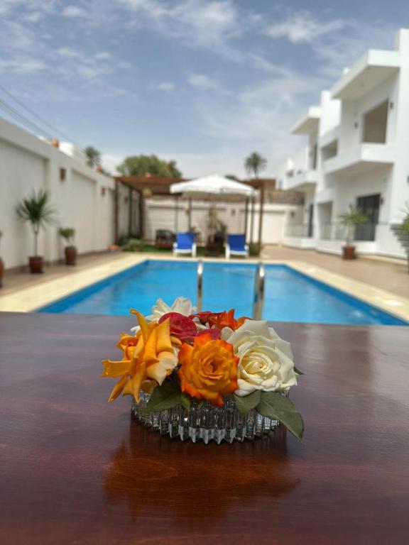 a vase of flowers on a table next to a pool at Malak house swimming pool &Garden in Luxor