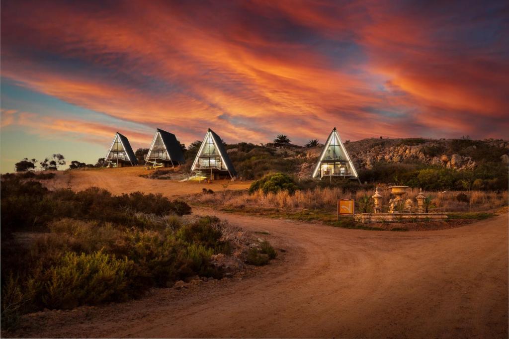 a dirt road with a group of triangular buildings on a hill at Peace Haven @ Windfarm Accommodation in Yzerfontein