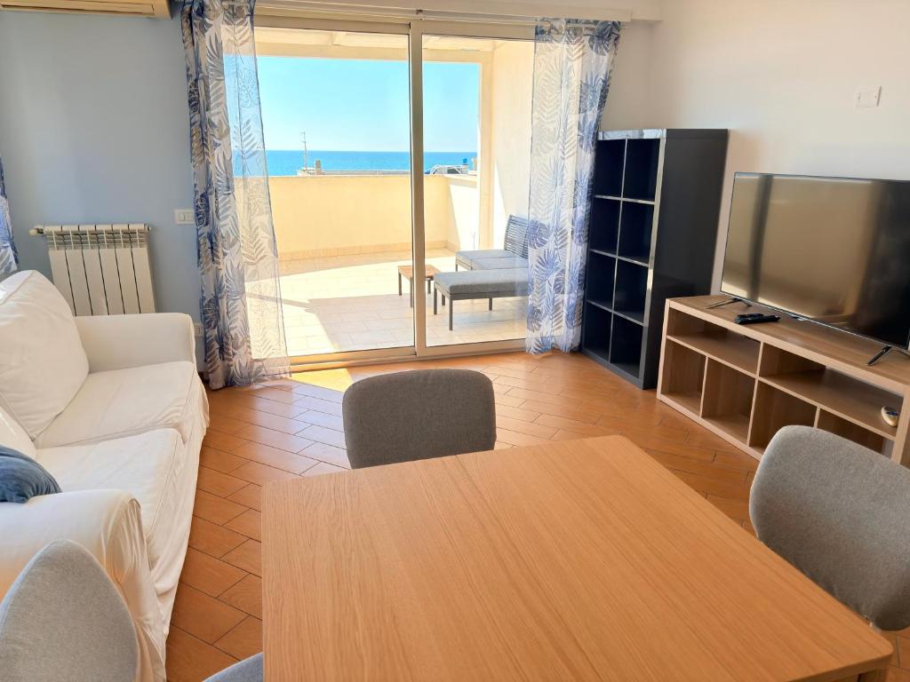 a living room with a couch and a table and a television at Meduse Seafront - Attico al Mare in Torvaianica