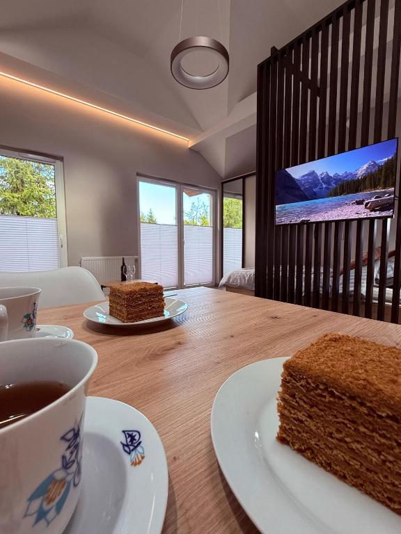 a table with a cup of coffee and a piece of cake at Apartament 59 Bystra Park in Bystra