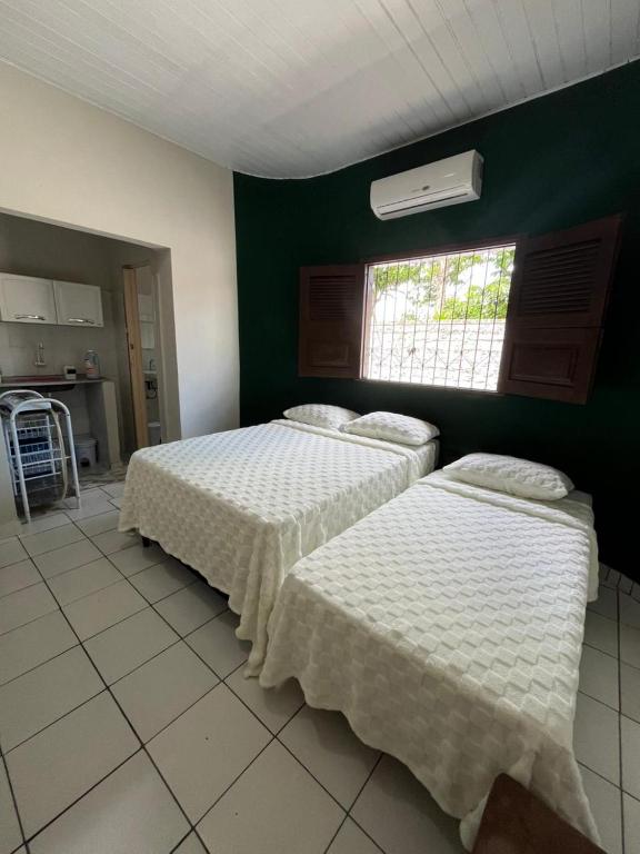 two beds in a room with a green wall at Estação 48 in Castanhal