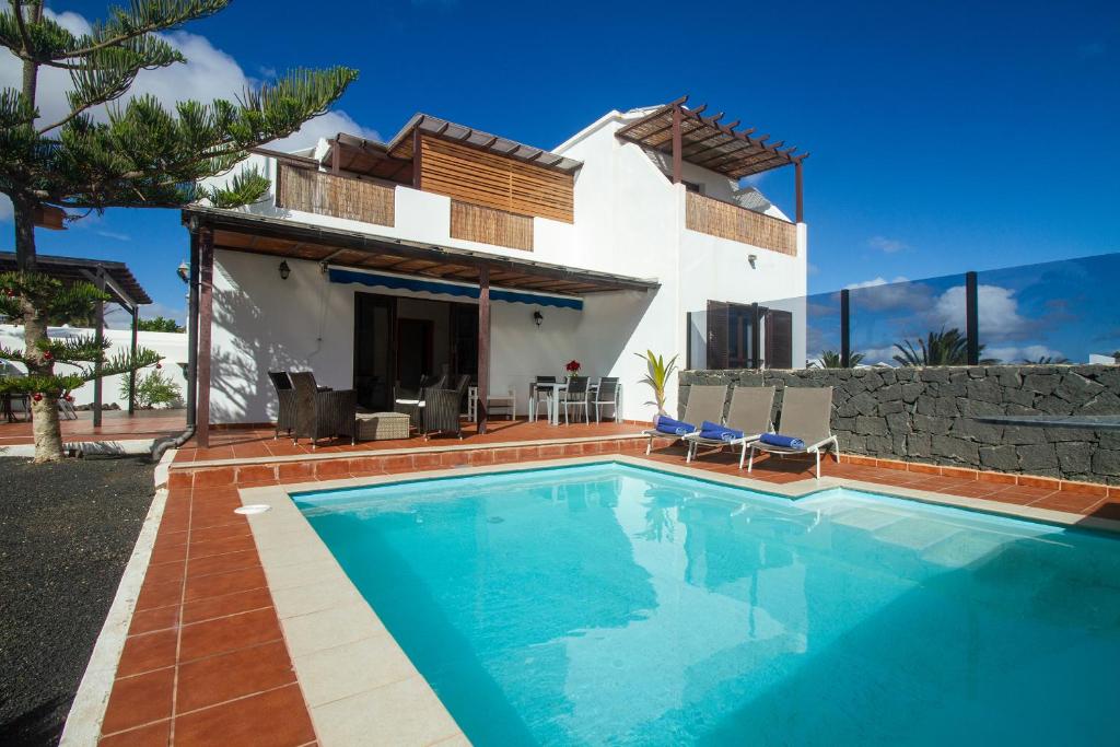 a villa with a swimming pool in front of a house at Niteo House in Costa Teguise