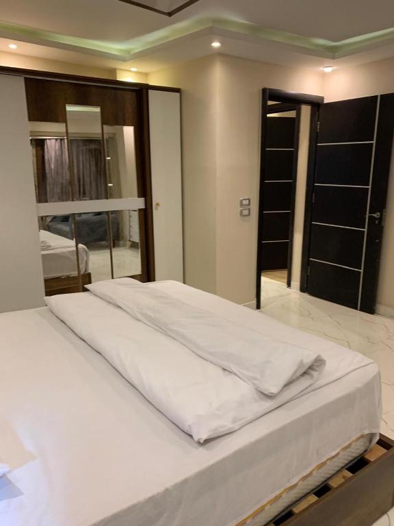 a large white bed in a room with a mirror at 18B Shehb Apartment Hotel in Giza