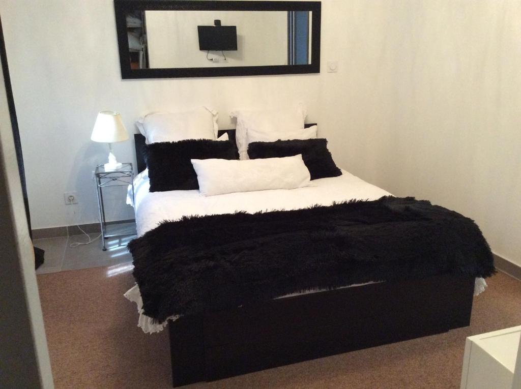 La Maison d'Estelle في Lavérune: غرفة نوم مع سرير مع وسائد سوداء وبيضاء