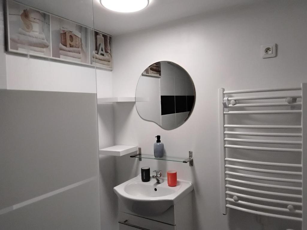 a white bathroom with a sink and a mirror at Ty Menic in Lesneven