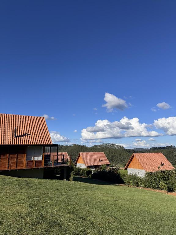 a house with a green field and some buildings at Chalés Grecco in Venda Nova do Imigrante