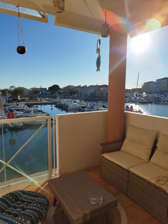 a balcony with a couch and a view of a marina at La Terrasse des Voiliers in Frontignan