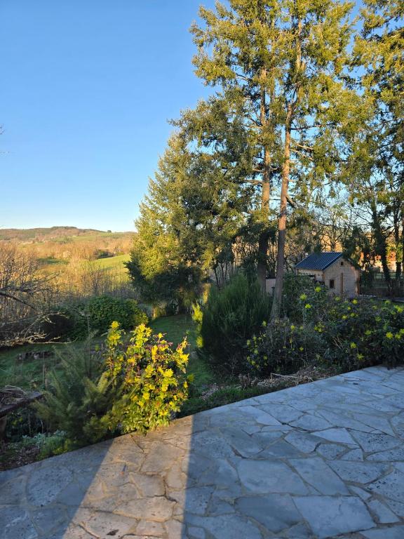 a stone walkway in a garden with trees and flowers at Edelweiss in Moux-en-Morvan