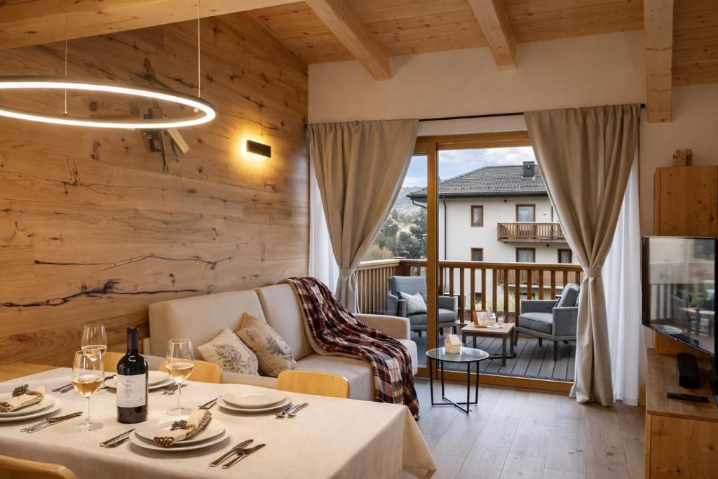 a living room with a table and a balcony at ALPINE LOFT - Residence Veronza con piscina, Dolomiti Affitti in Cavalese
