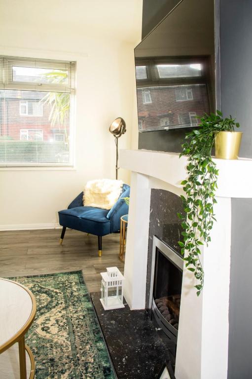 a living room with a fireplace and a blue couch at 3 Bed - Shefa Homes in Manchester