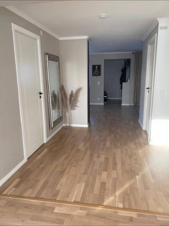 an empty living room with a wooden floor and white walls at Workers Stay - Temporary House Stockholm in Rönninge