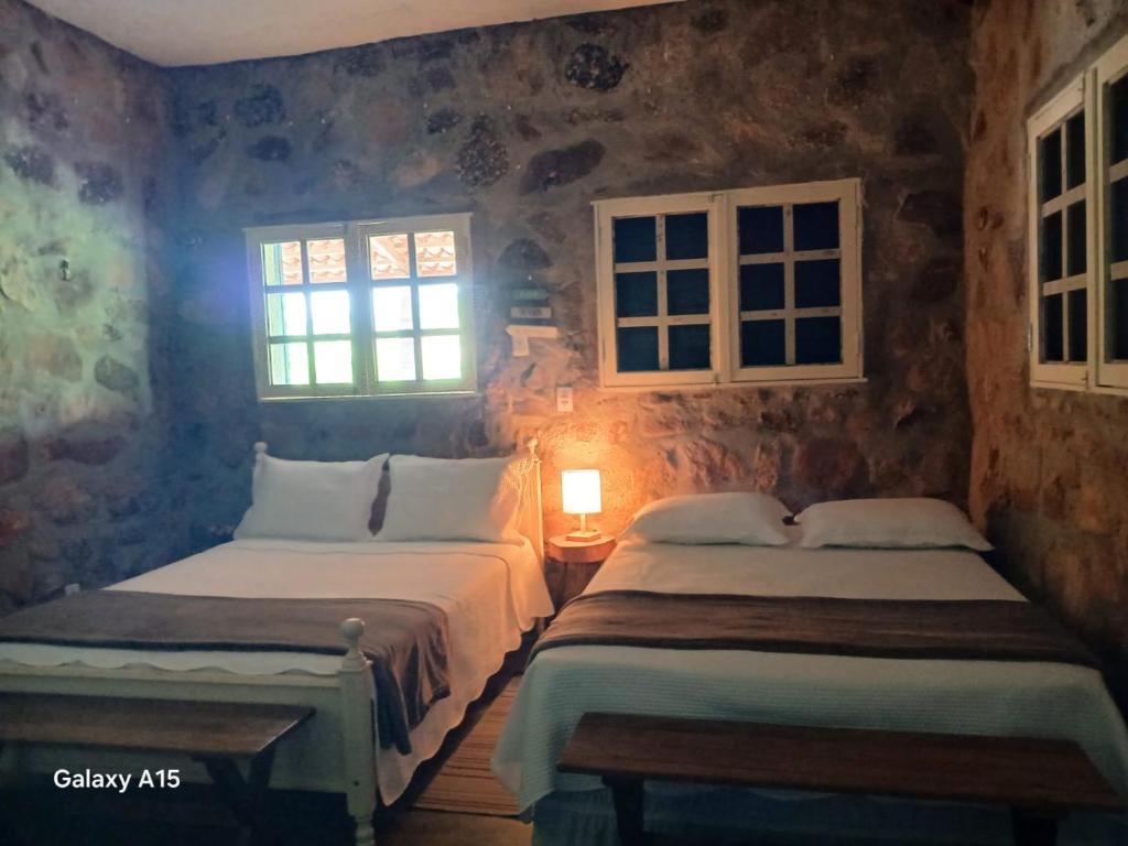 two beds in a room with two windows at Chalé Encontro das Pedras na Serra in Serra de São Bento