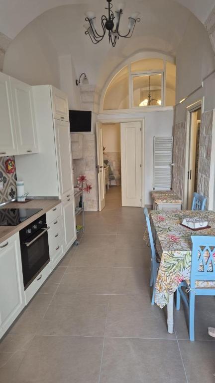 a kitchen with white cabinets and a table and a dining room at Casa Coppaiaia - Spaziosa e luminosa nel centro storico in Martina Franca