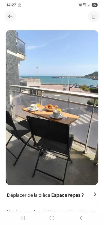 a table with a plate of food on a balcony at Superbe appartement face à la mer à Erquy in Erquy