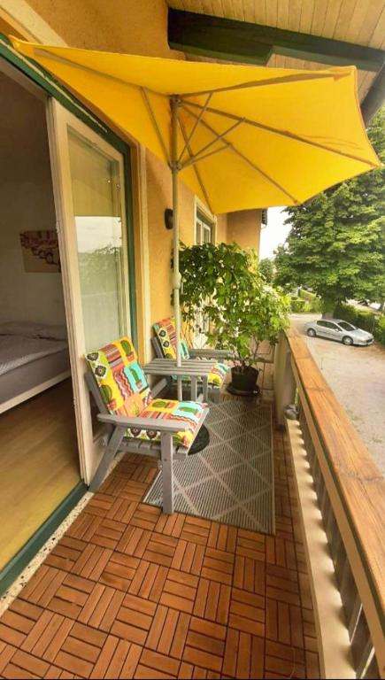 a patio with a yellow umbrella and chairs on a porch at Barbara's Zimmer im Zentrum in Velden am Wörthersee