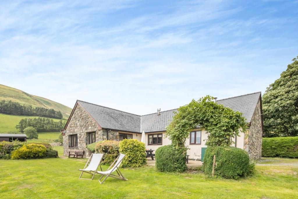 a house with two lawn chairs in front of it at 4 Bed in Tywyn oc-23385 in Llanfihangel-y-Pennant