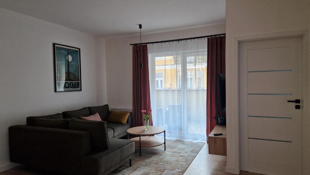 a living room with a couch and a table and a window at Apartament Bellissima in Bielsko-Biała