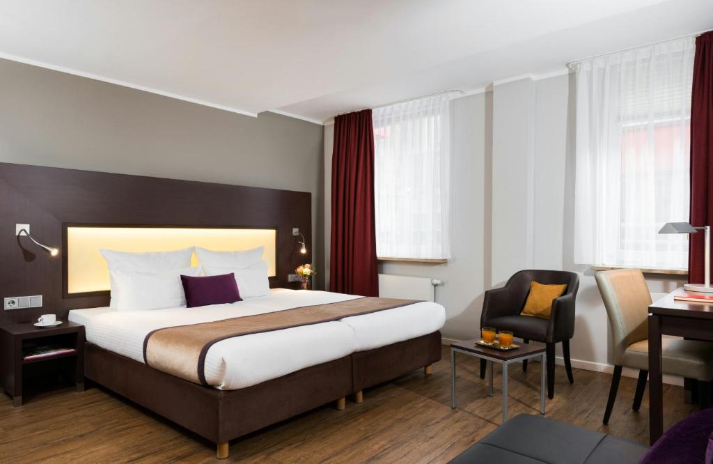 a hotel room with a bed and a chair at Leonardo Hotel München City Center in Munich