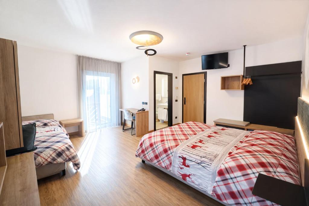 a bedroom with two beds and a desk in it at Pier Hotel in Andalo