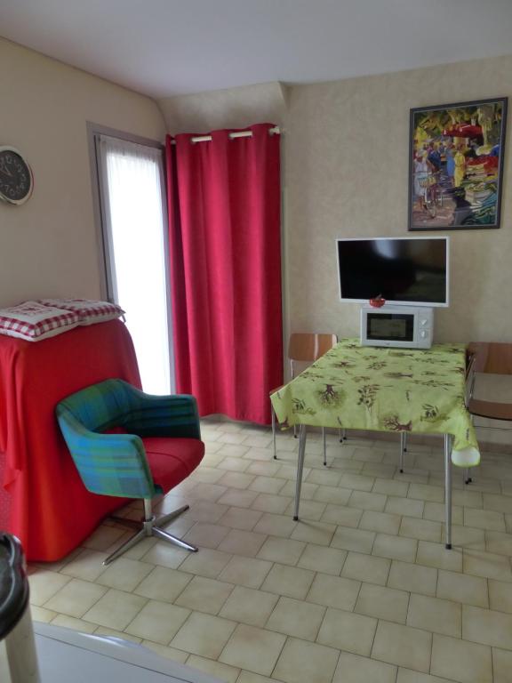 a living room with red curtains and a table and a television at Pied A Terre in Amélie-les-Bains-Palalda