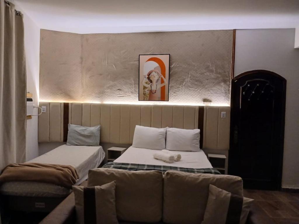 a small room with two beds and a couch at Aconchego - Centro in Miguel Pereira