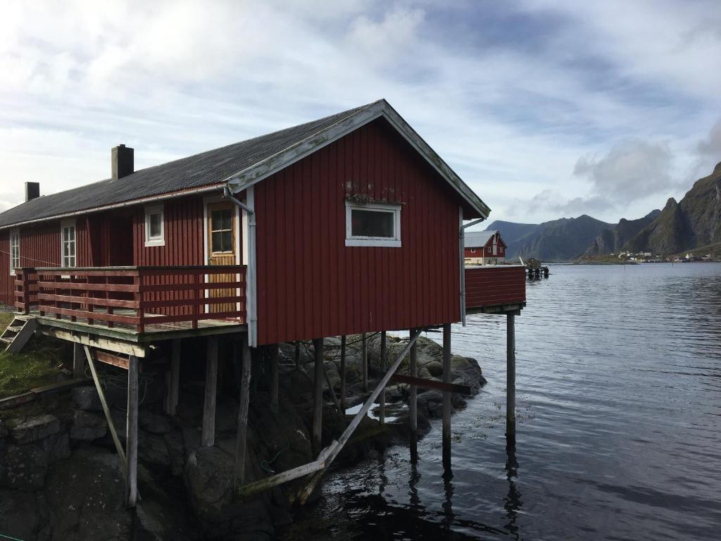 a red house on a dock in the water at Buodden Rorbuer - Fisherman Cabins Sørvågen in Sørvågen