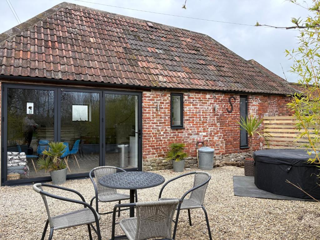 a patio with a table and chairs in front of a building at Hares Barn in Trowbridge