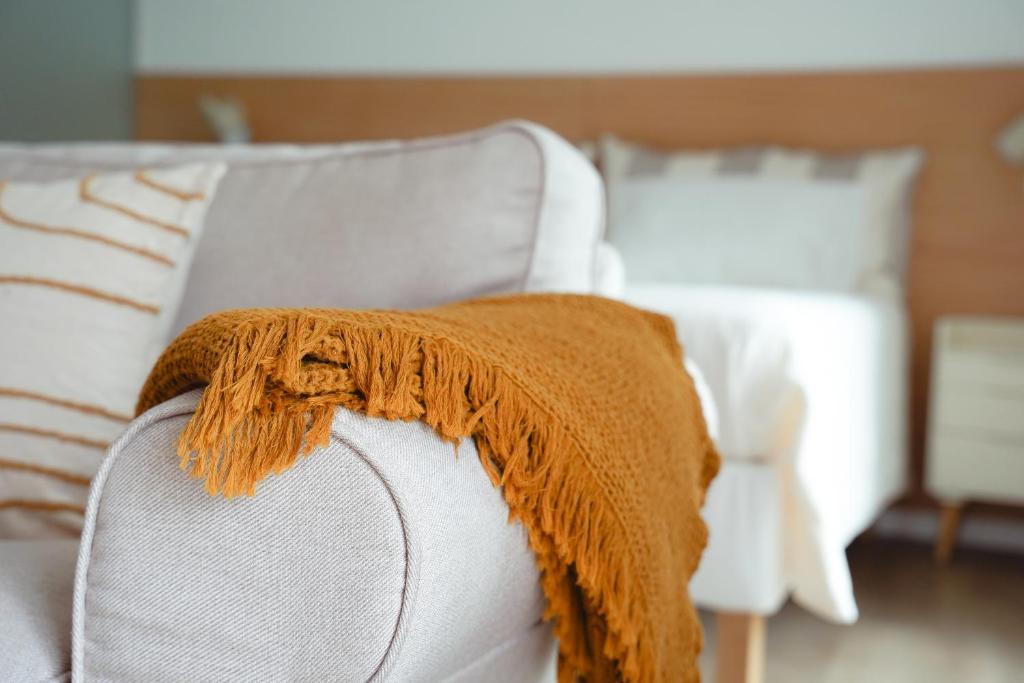 a brown blanket on the back of a white couch at OKTO Beach Loft in Praia do Almoxarife