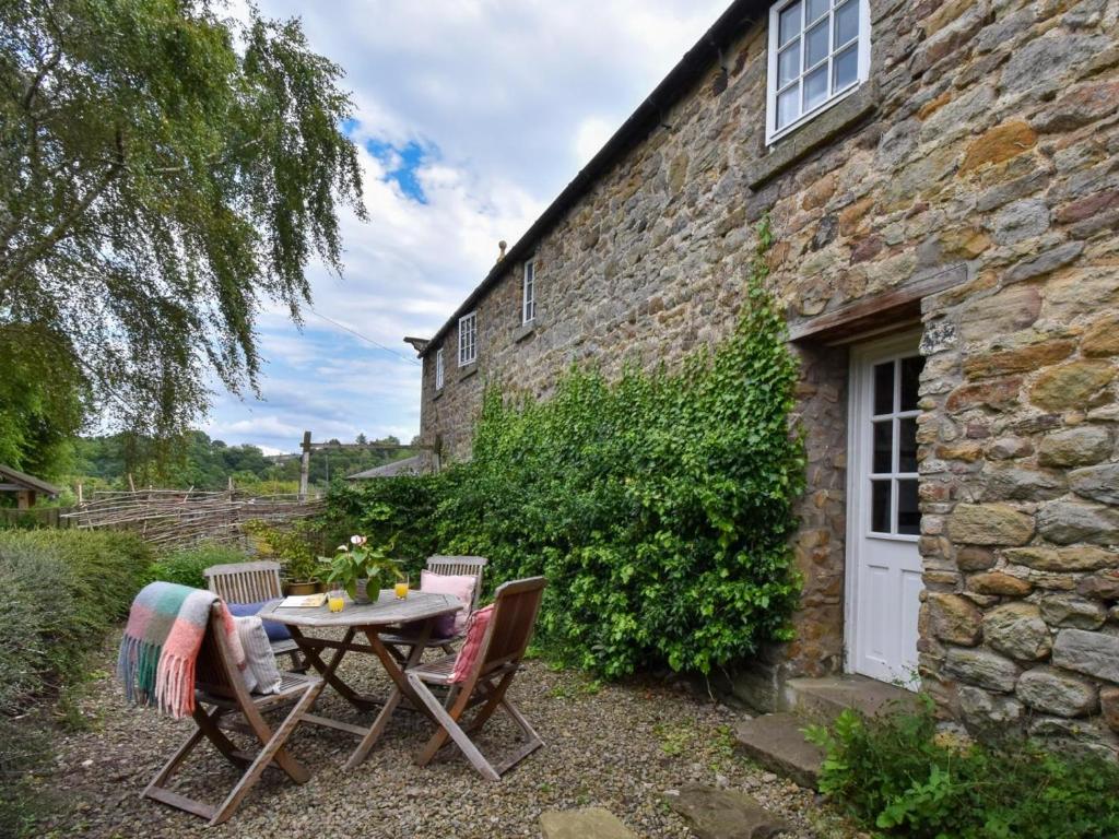 a table and chairs in front of a stone building at 3 Bed in Stocksfield oc-32252 in Stocksfield