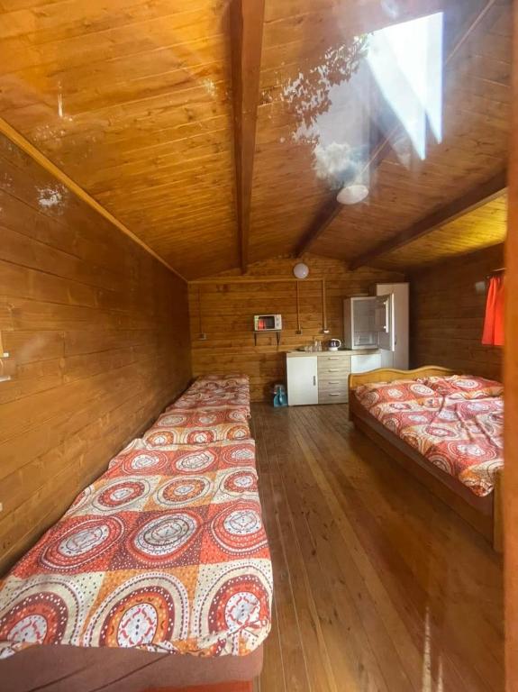 a bedroom with two beds in a room with wooden walls at Chaty oddych pri vode, aj pre rybárov in Veľké Úľany