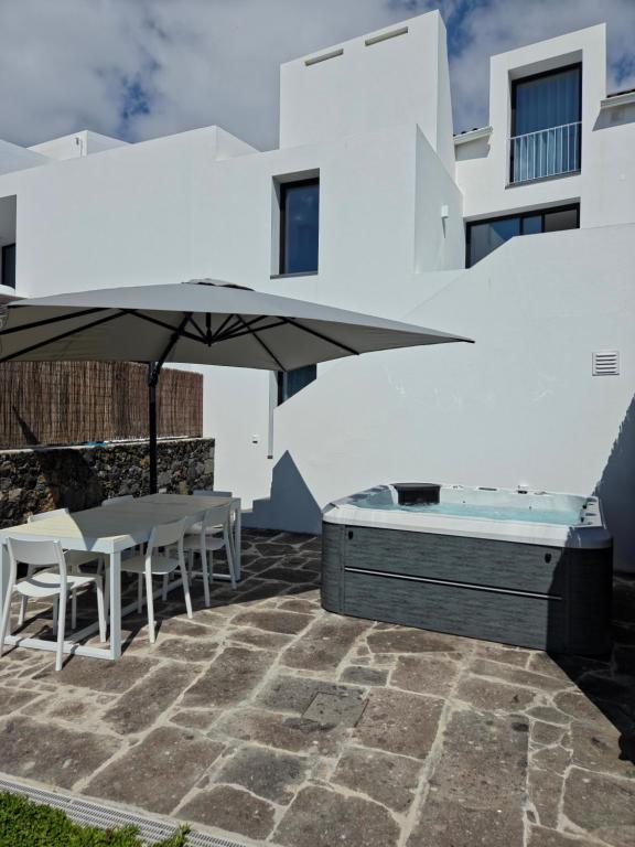 a patio with a hot tub and an umbrella at Oceanside Village 2 in Lagoa