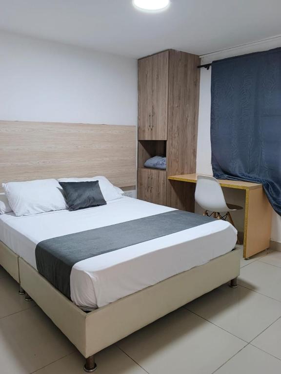 a bedroom with a large bed and a desk at Hotel pasarela real cali in Cali