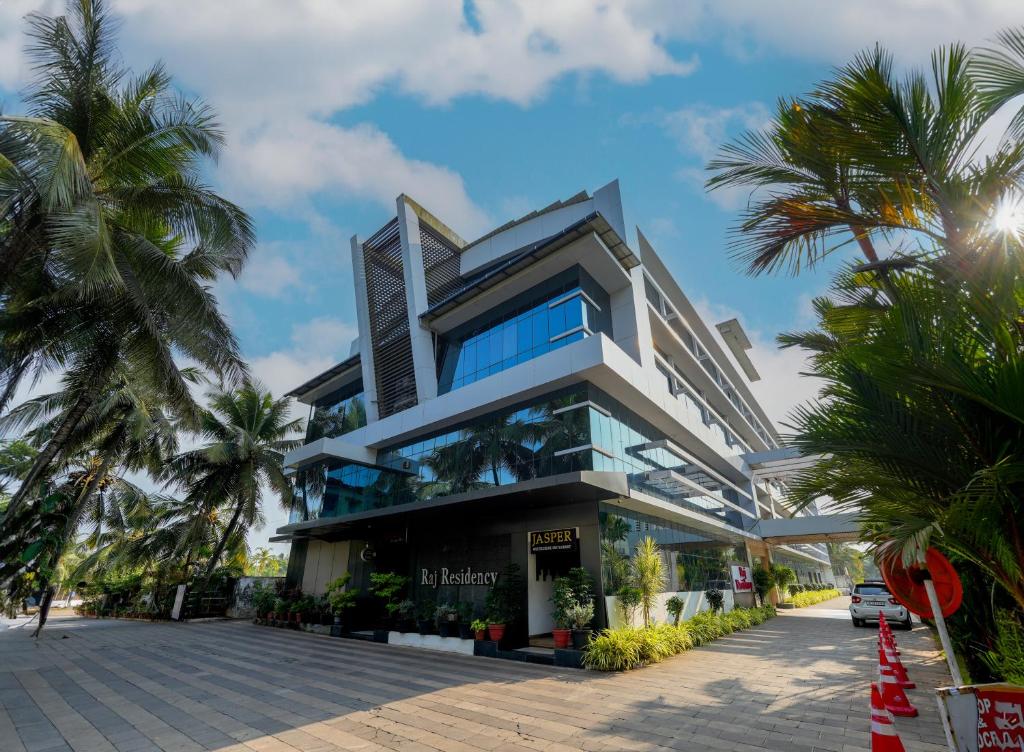 a building with palm trees in front of it at Raj Residency in Hosdrug