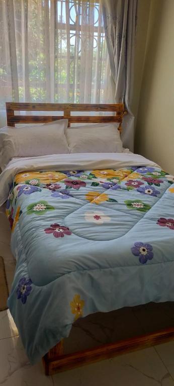 a bed with a blue comforter with flowers on it at Green Garden in Juja