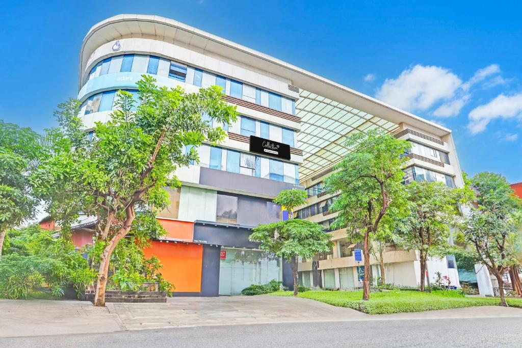 an apartment building with trees in front of it at Super Collection O Adajan Formerly Hotel Western Inn in Surat