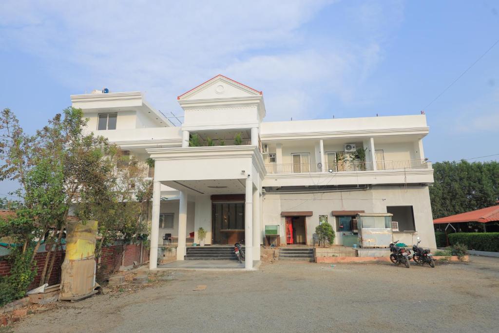 a white house with two motorcycles parked in front of it at Srushti Resort in Daulatābād