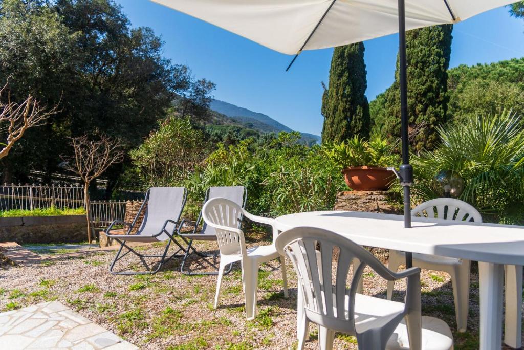 a white table and chairs with an umbrella at Il Golfo e La Spiaggia - A Due Passi Da Procchio in Marciana